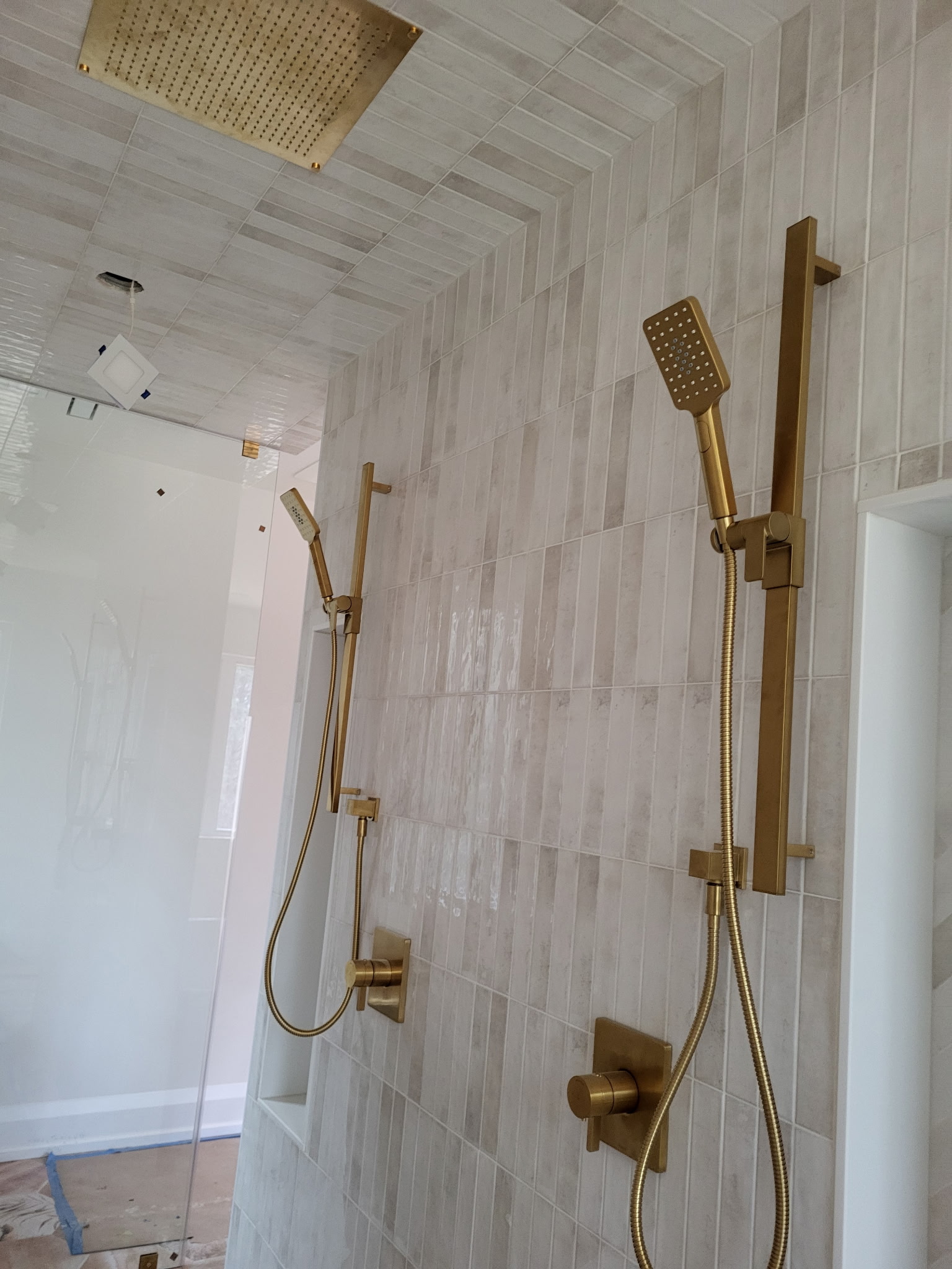 Walk-in shower with dual gold rain heads and custom tile
