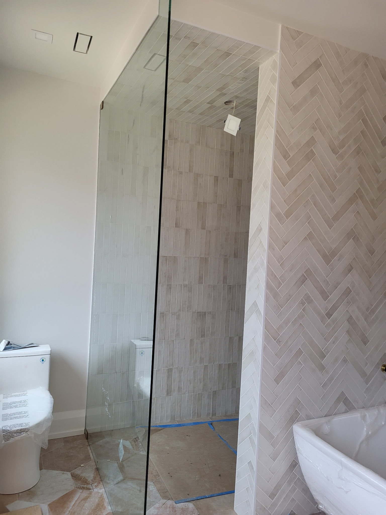 Full bathroom with frameless glass shower and herringbone accent wall
