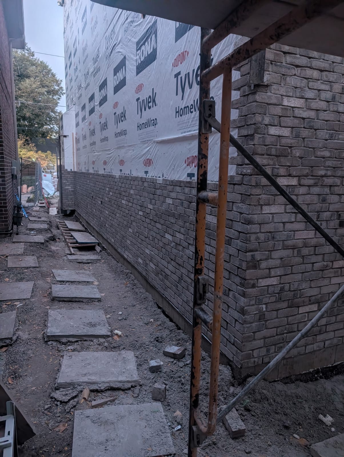 Brick masonry wall construction with stone paver walkway