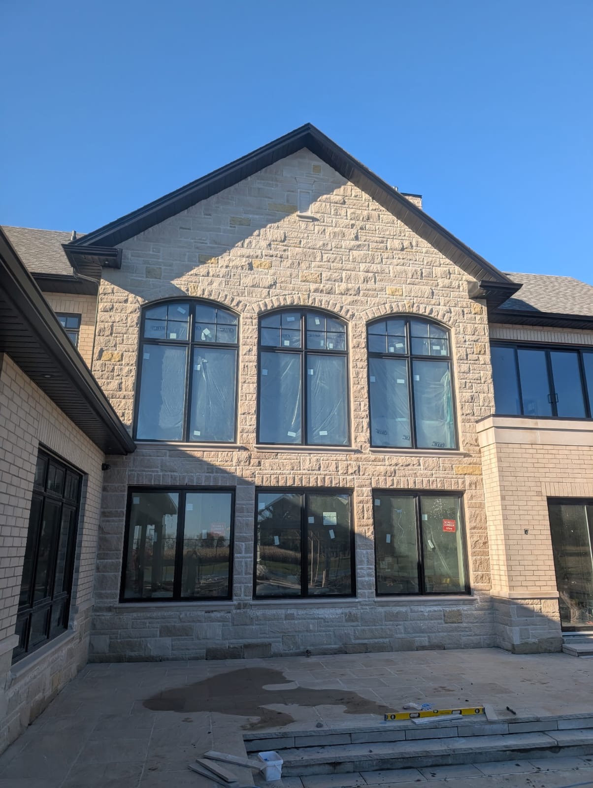 Natural stone home facade with arched windows and professional masonry